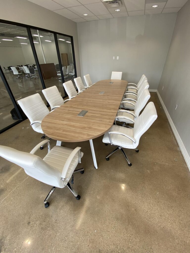 wooden conference table with white chairs